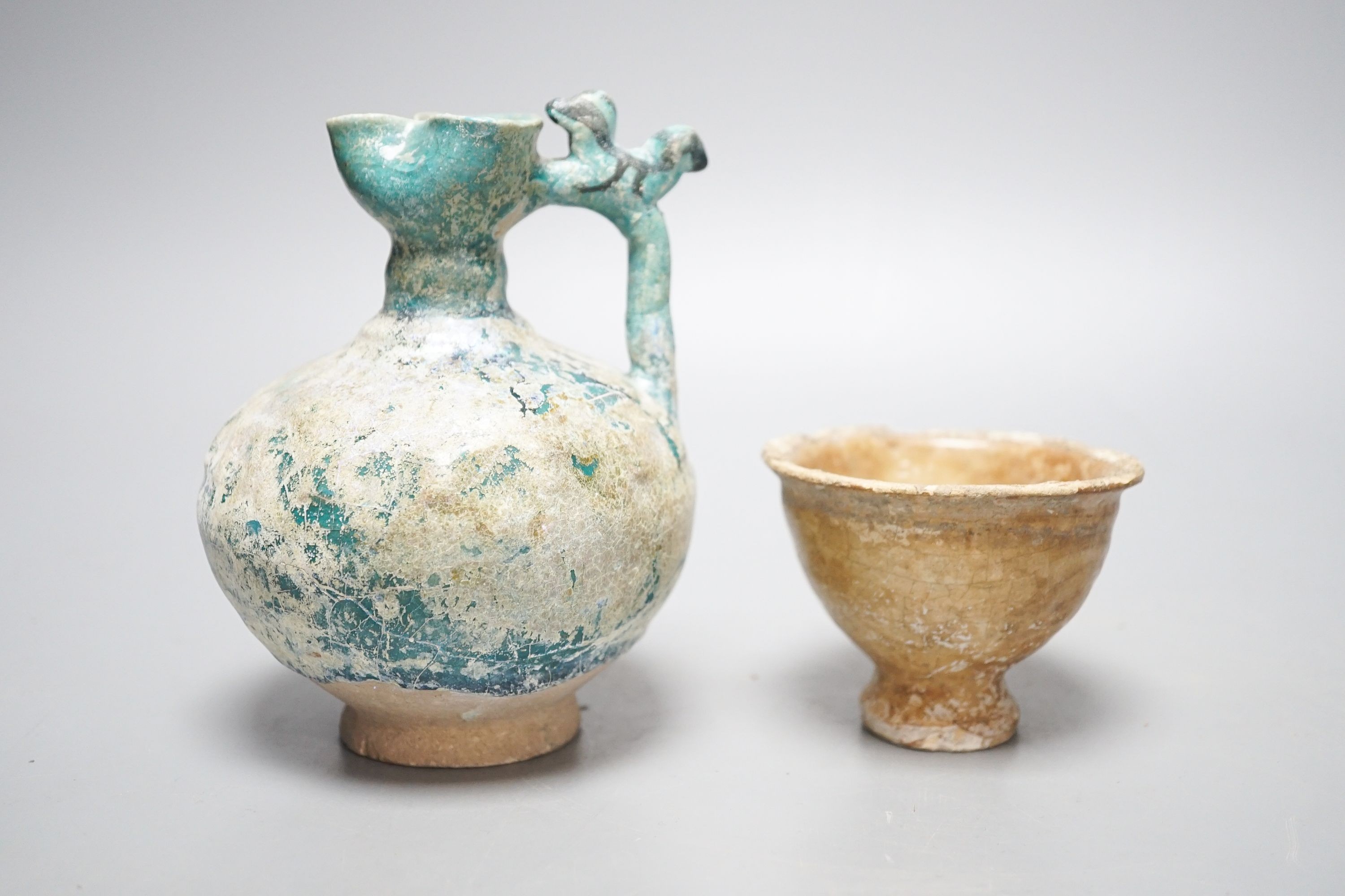 A Kashan turquoise glazed pottery ewer, 14th century, with mineral iridescence and an early Islamic pottery cup 14cm